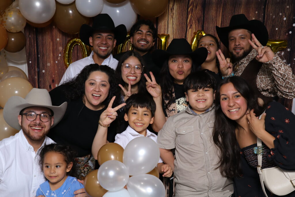 Guests laughing and posing at a rustic cowboy-style bridal shower photo booth in Dallas, TX.